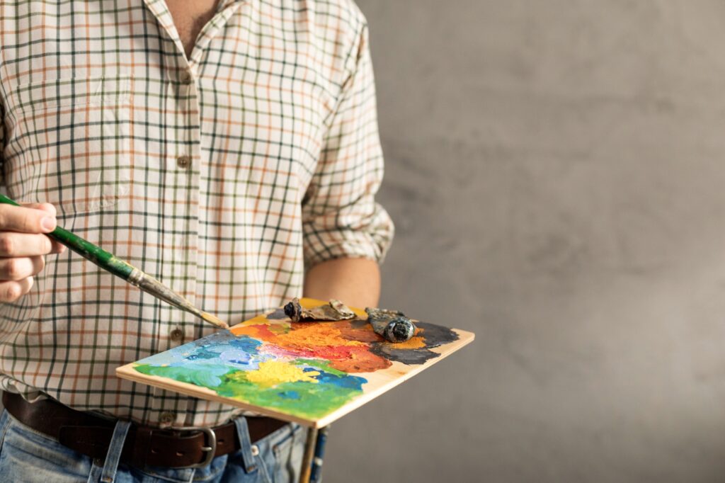 Male artist holding palette and paintbrush. Man artist painter and paint brush